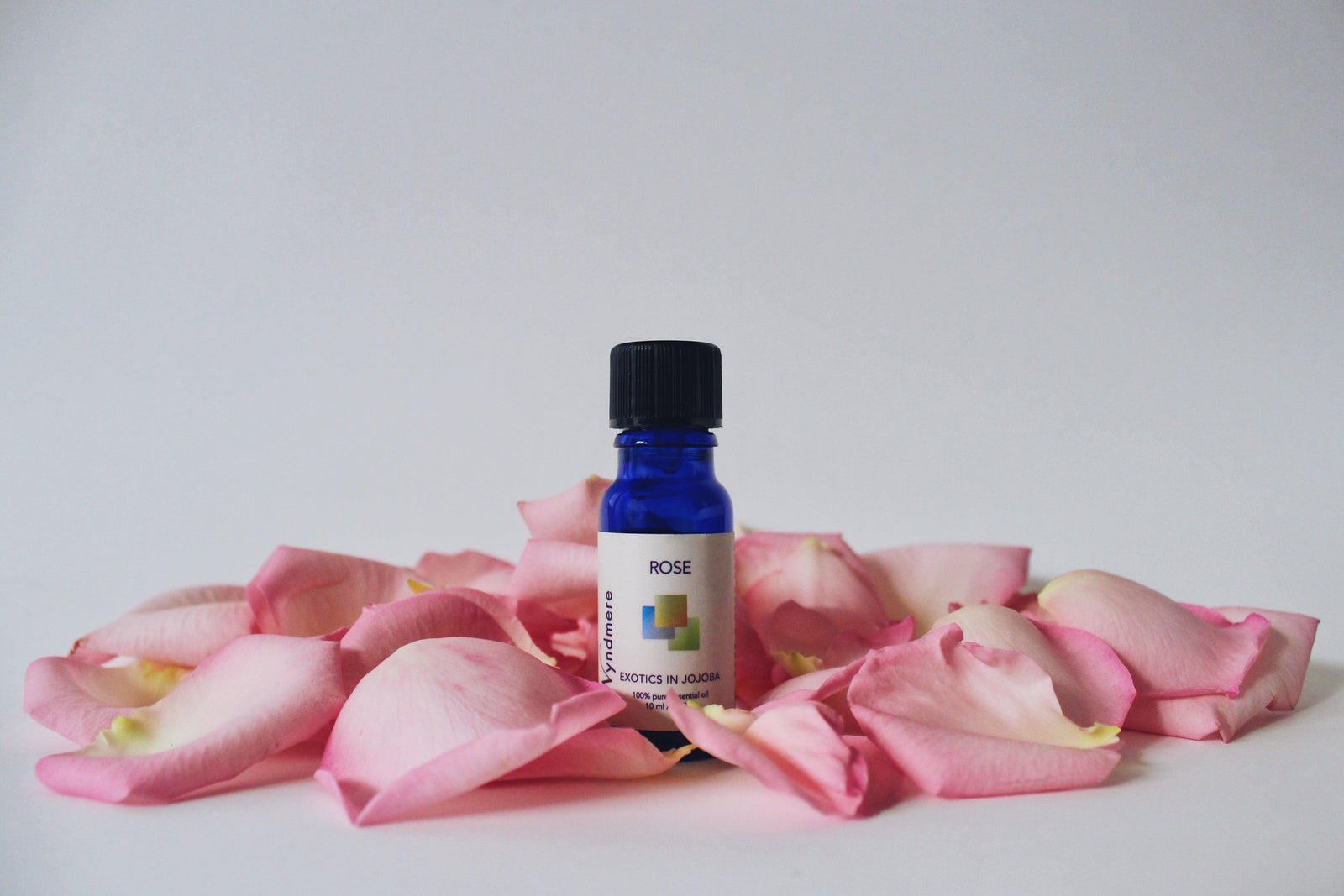 10ml bottle of Wyndmere Rose in Jojoba surrounded by rose petals