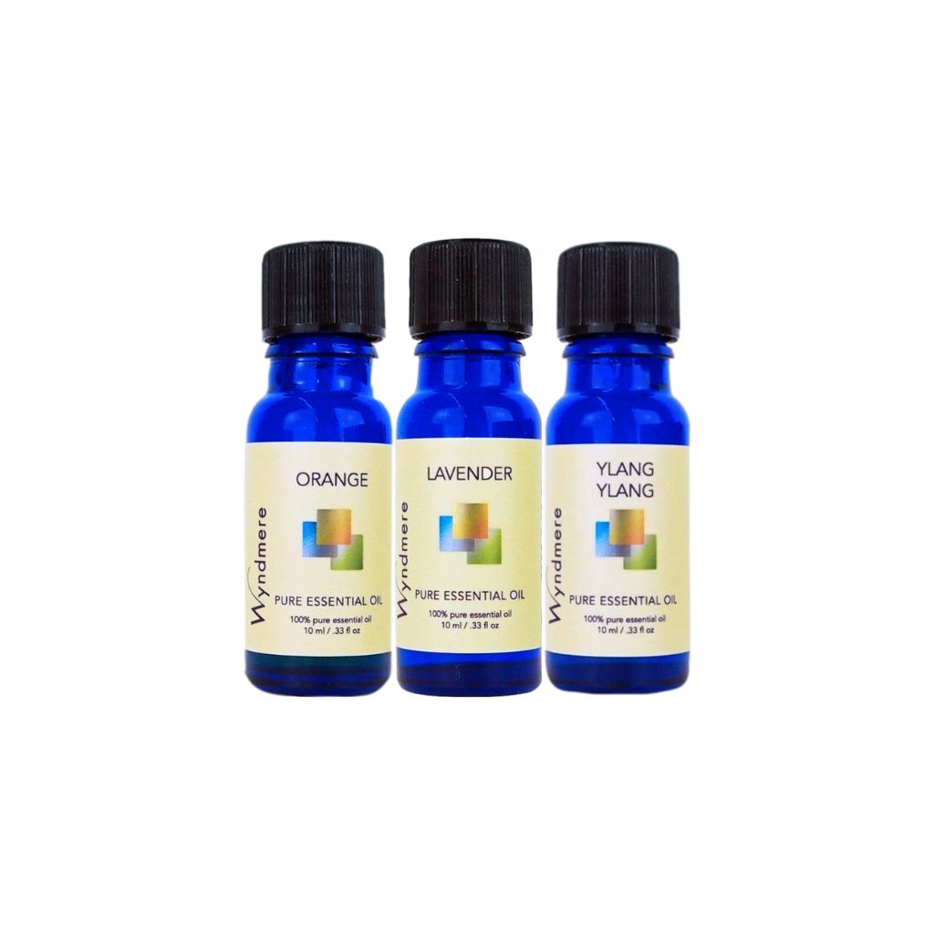 Orange, Lavender, and Ylang Ylang essential oils in blue bottles on a white background.