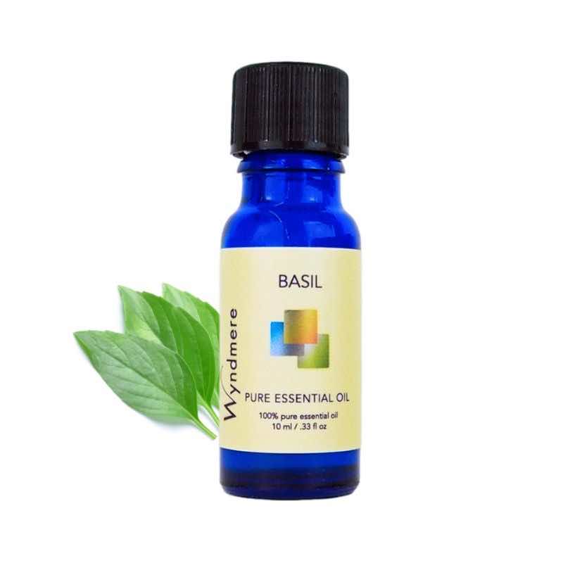 Basil leaves with a 10ml cobalt blue bottle of Wyndmere Basil Essential Oil