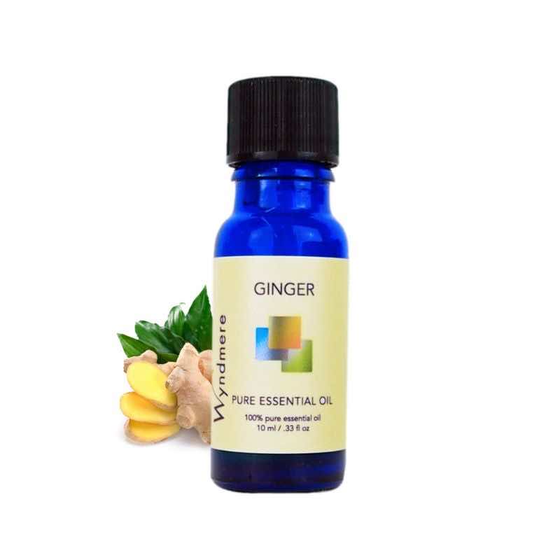 Slices of fresh ginger root with a 10ml cobalt blue bottle of Wyndmere Ginger Essential Oil