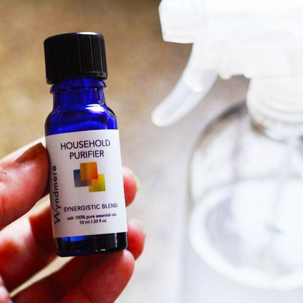Bottle of Household Purifier essential oil blend next to large spray bottle used for making cleaning solution