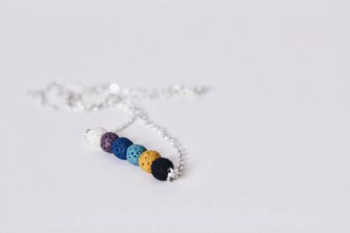 aromatherapy necklace of multicolored lava beads on a silver chain laying on table