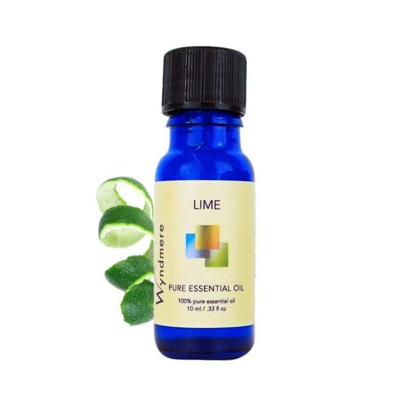 Curled lime peel with a 10ml cobalt blue bottle of Wyndmere Lime Essential Oil