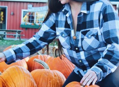 woman in a pumpkin patch wearing aromatherapy necklace with bronze pendant on a gold-toned chain