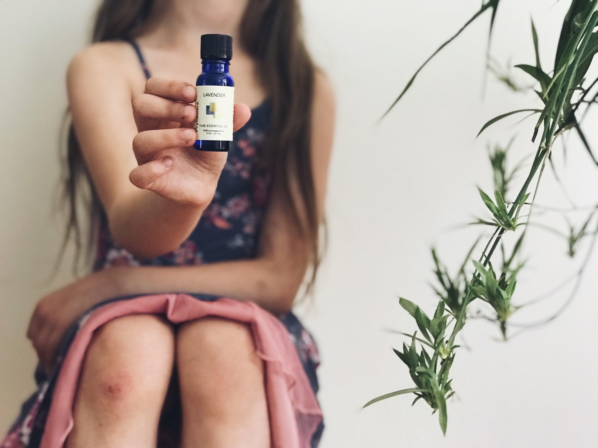 Sitting girl holding Wyndmere lavender essential oil