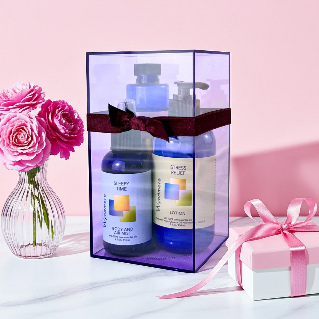 Three bottles of skincare products in a clear box with pink flowers and a gift box on a light pink background.