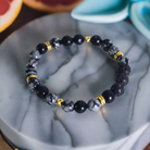 Black beaded bracelet with gold accents on a marble surface