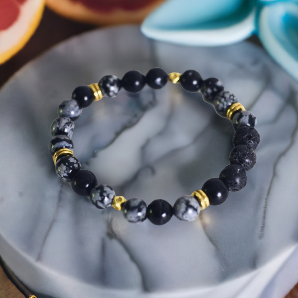 Black beaded bracelet with gold accents on a marble surface