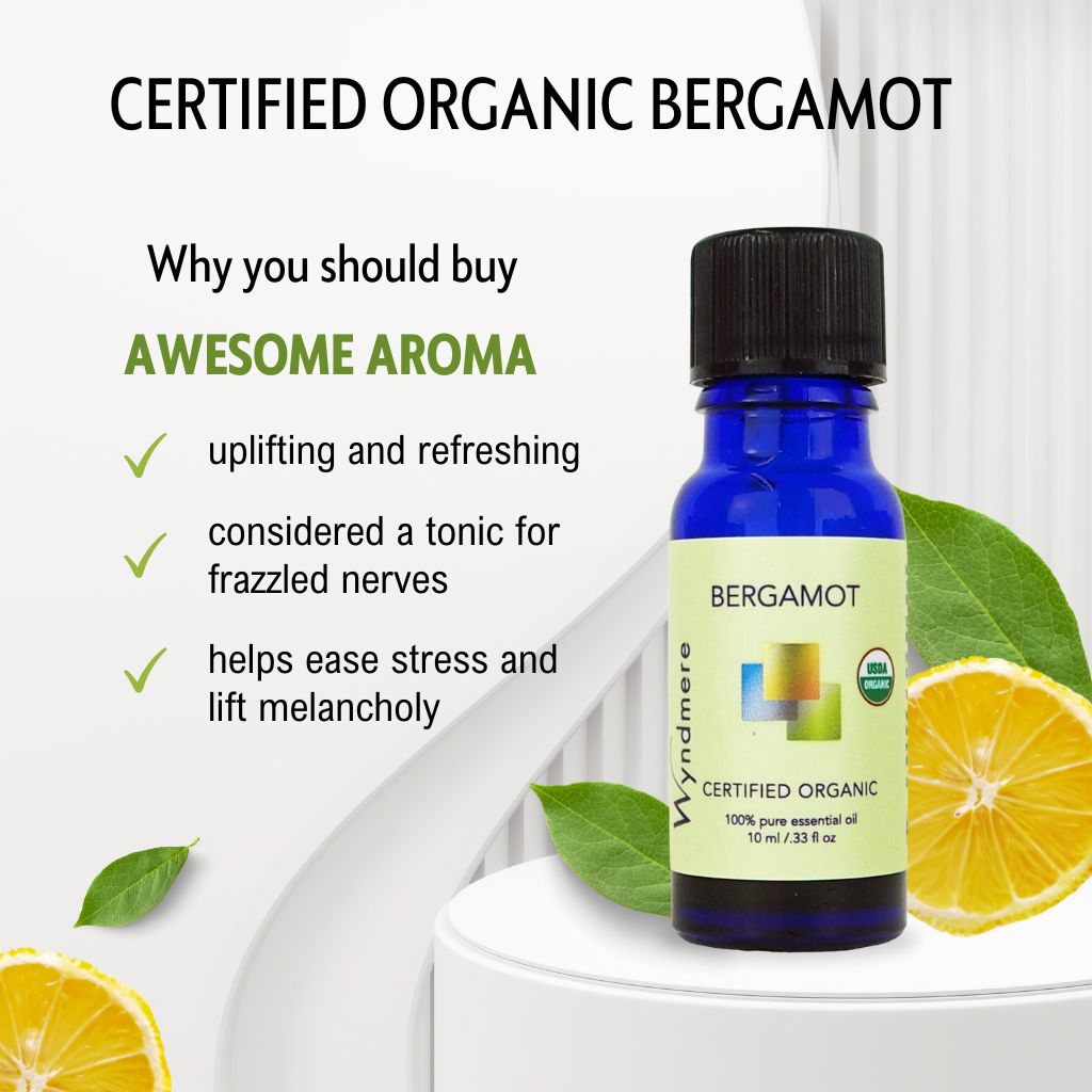 Bottle of certified organic Bergamot essential oil with lemon slices and green leaves on a white background