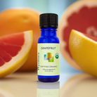Bottle of Wyndmere certified organic Grapefruit essential oil with grapefruit halves in the background