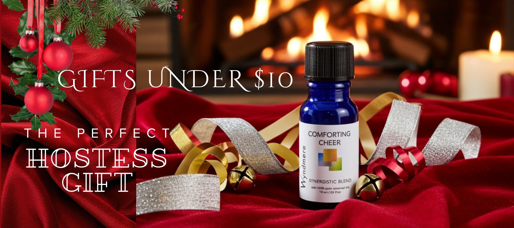 Bottle of 'Wyndmere Comforting Cheer' essential oil on a red fabric with Christmas decorations and text about gifts under $10.