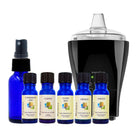 Set of blue essential oil bottles with labels and a black electronic device on a white background