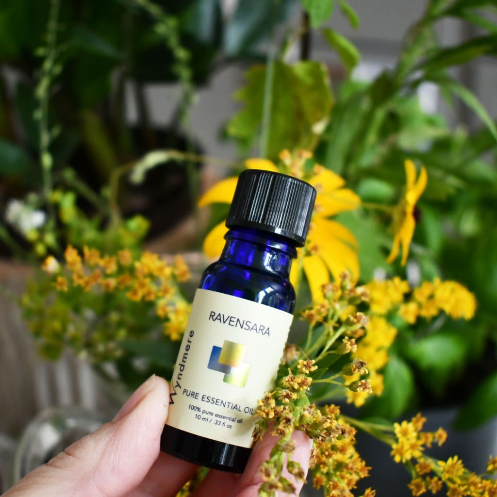 Bottle of Wyndmere Ravensara essential oil on a background of flowers