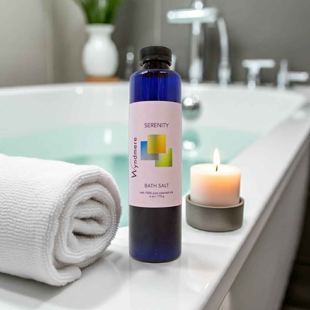 Wyndmere bottle of Wyndmere Serenity bath salt with a candle and towel on a bathtub edge.