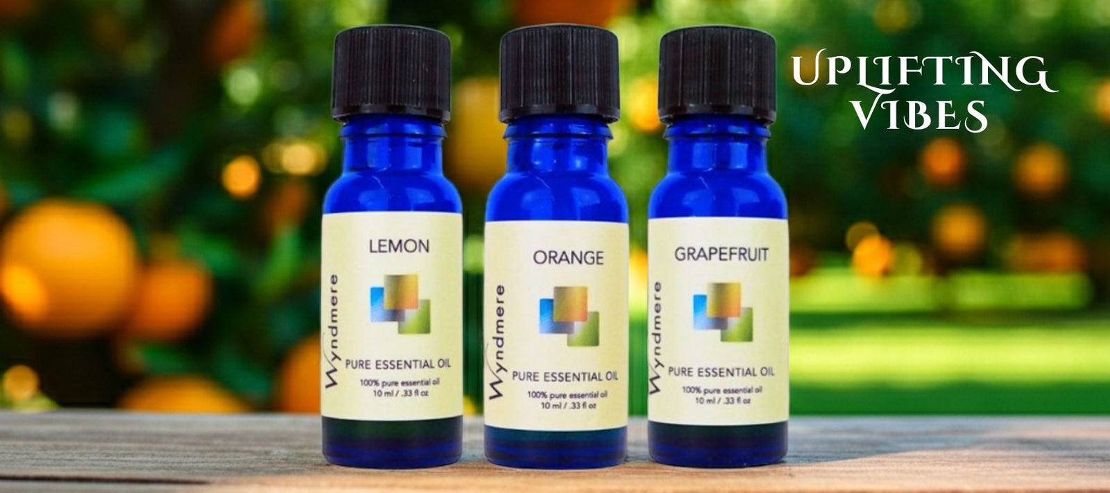 Three essential oil bottles labeled 'Lemon', 'Orange', and 'Grapefruit' on a wooden surface with fruits in the background.