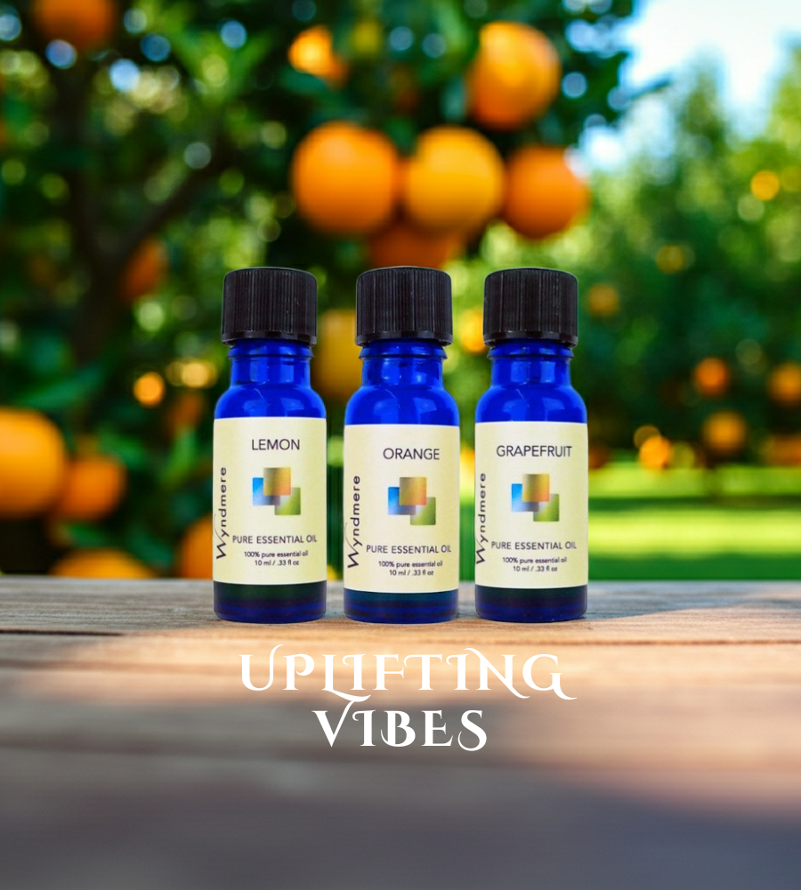 Three essential oil bottles labeled 'Lemon', 'Orange', and 'Grapefruit' with a blurred background of oranges.
