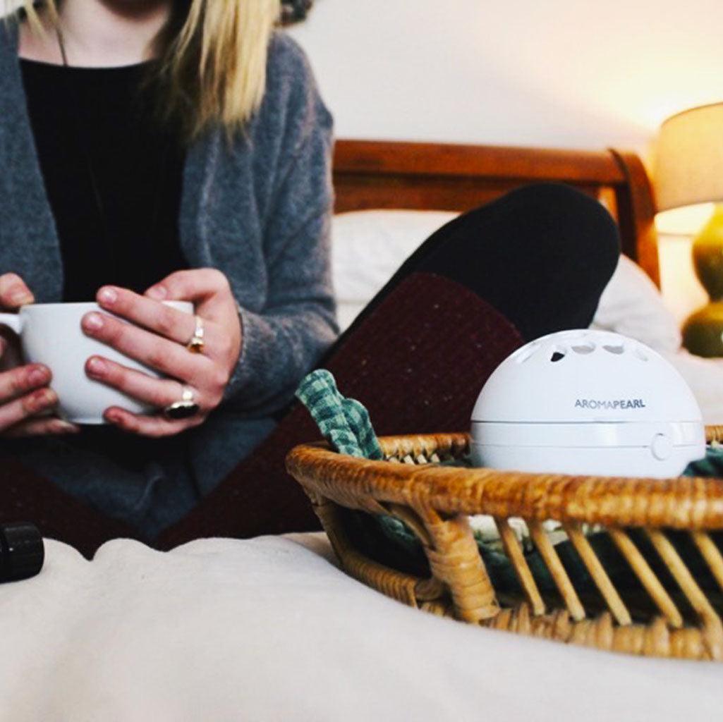 Woman sitting on bed with White AromaPearl in a basket