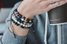woman wearing 5 aromatherapy bracelets on wrist while cradling a cup of coffee