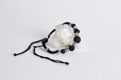 black corded aromatherapy bracelet with black lava beads laying on quartz stone