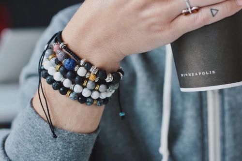 woman wearing 5 aromatherapy bracelets on wrist while holding a cup of coffee
