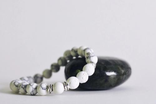 white beaded aromatherapy bracelet with white lava stones draped on black polished rock