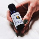 Female hand holding Wyndmere Balancing Essential Oil Blend in a 10ml cobalt blue bottle.