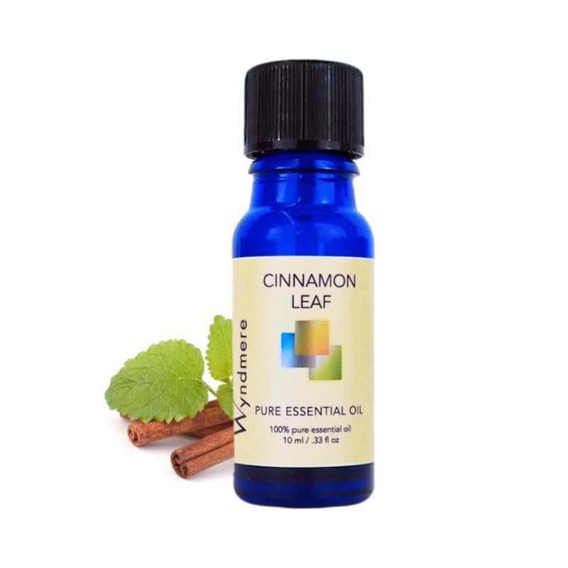 Cinnamon sticks and leaf with a 10ml cobalt blue bottle of Wyndmere Cinnamon Leaf Essential Oil