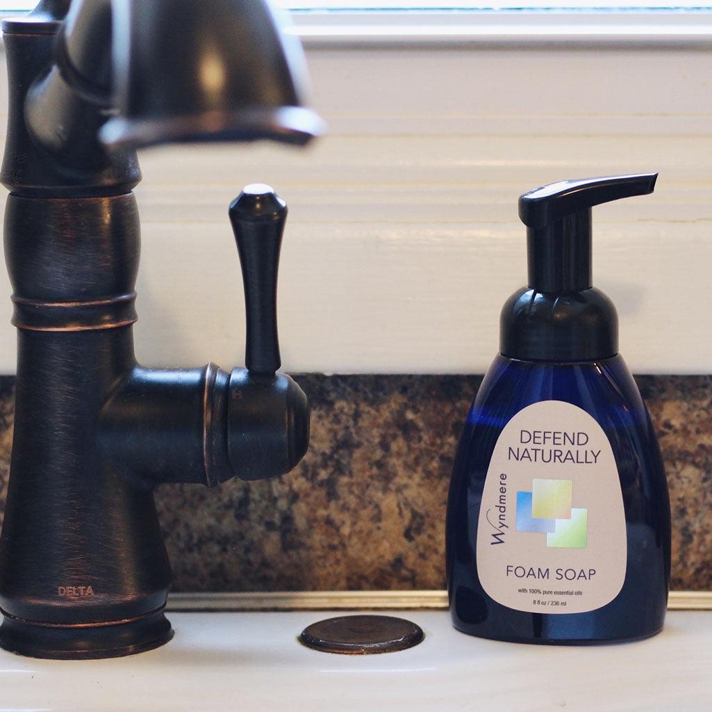 Cobalt blue bottle of Defend Naturally foam soap on counter by black kitchen faucet