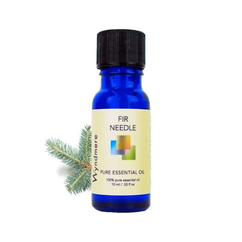 Fir sprig with a 10ml cobalt blue bottle of Wyndmere Fir Needle Essential Oil