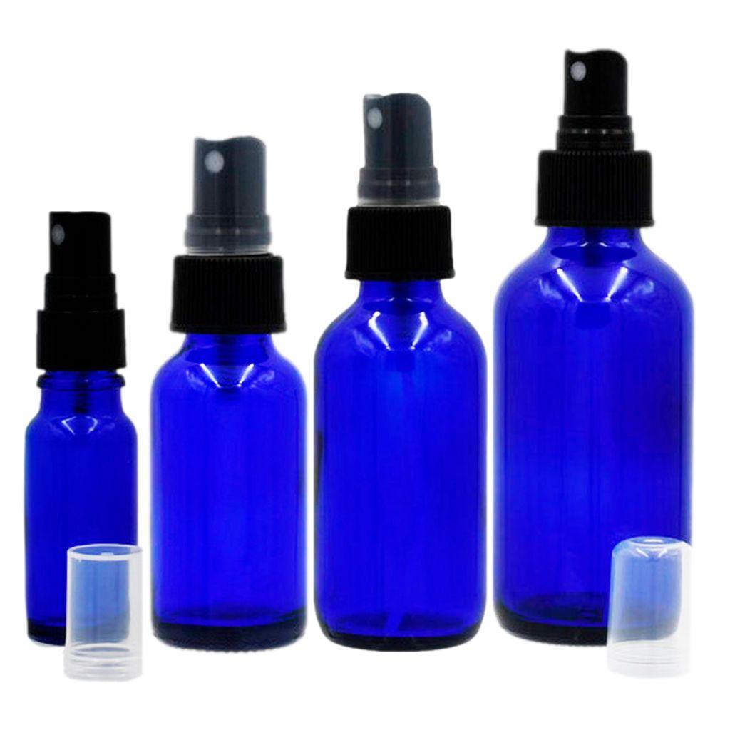Group cobalt blue boston round glass bottles with black fine spray mister with clear hood off on the table by the bottle