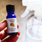 Bottle of Household Purifier essential oil blend next to large spray bottle used for making cleaning solution