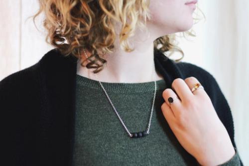 model wearing aromatherapy necklace of 3 black lava beads on a silver chain