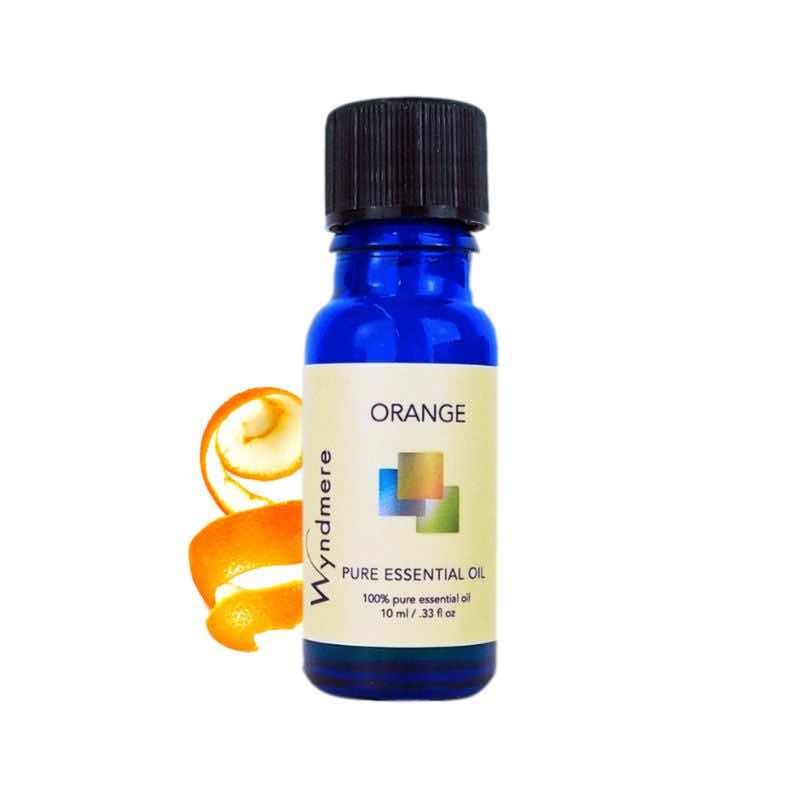 Curled orange peel with a 10ml cobalt blue bottle of Wyndmere Orange Essential Oil