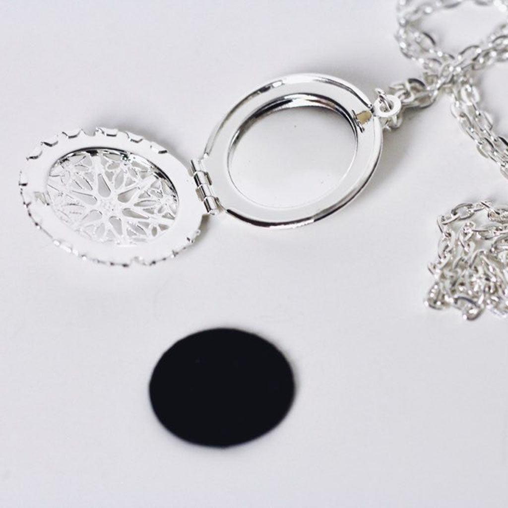 aromatherapy necklace with silver pendant open with fragrance pad laying near