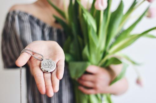 girl holding pink tulips and aromatherapy necklace with tree of life silver locket pendant on a silver chain