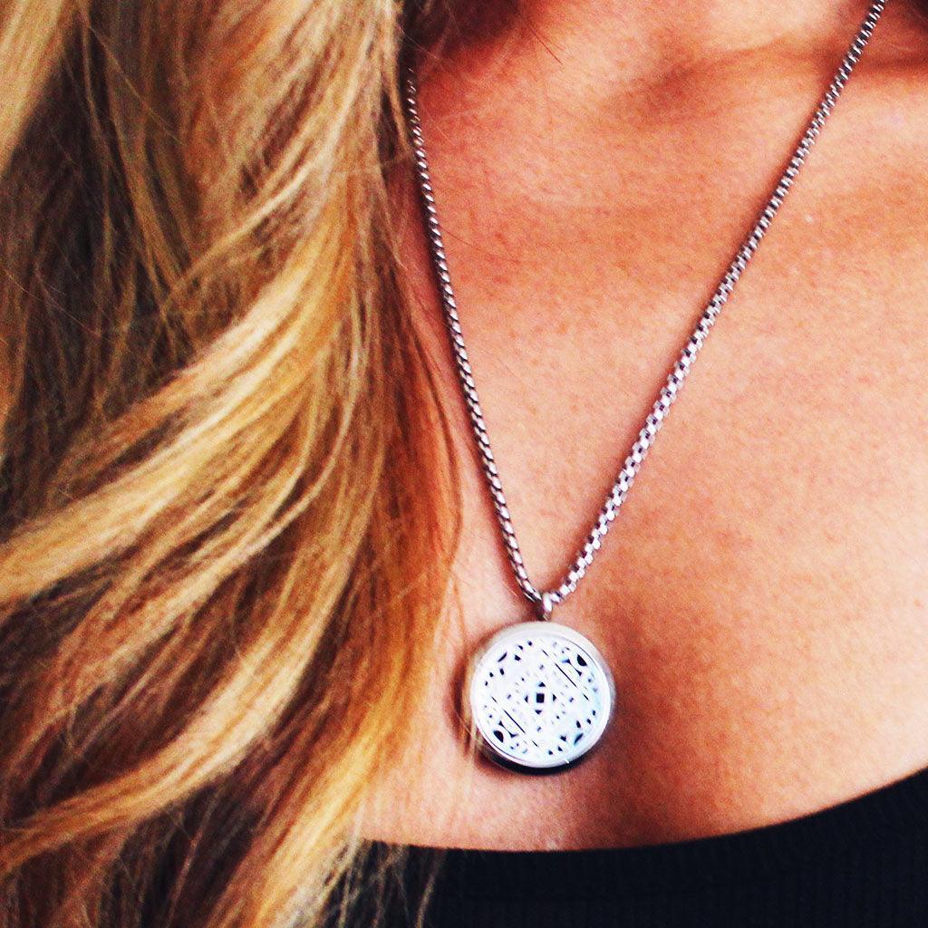 model wearing aromatherapy necklace with lacy silver locket pendant on a silver chain