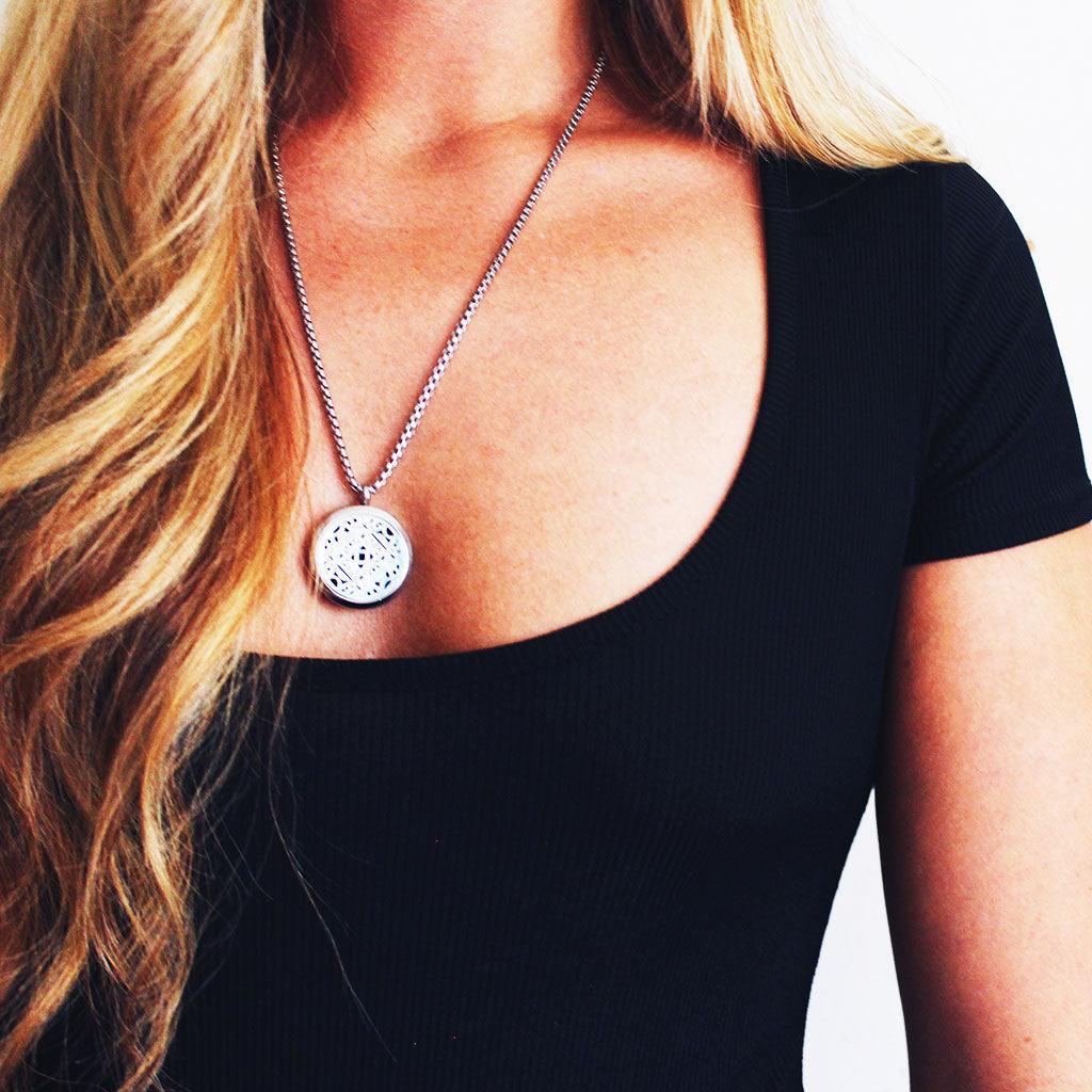 model wearing aromatherapy necklace with lacy silver locket pendant on a silver chain