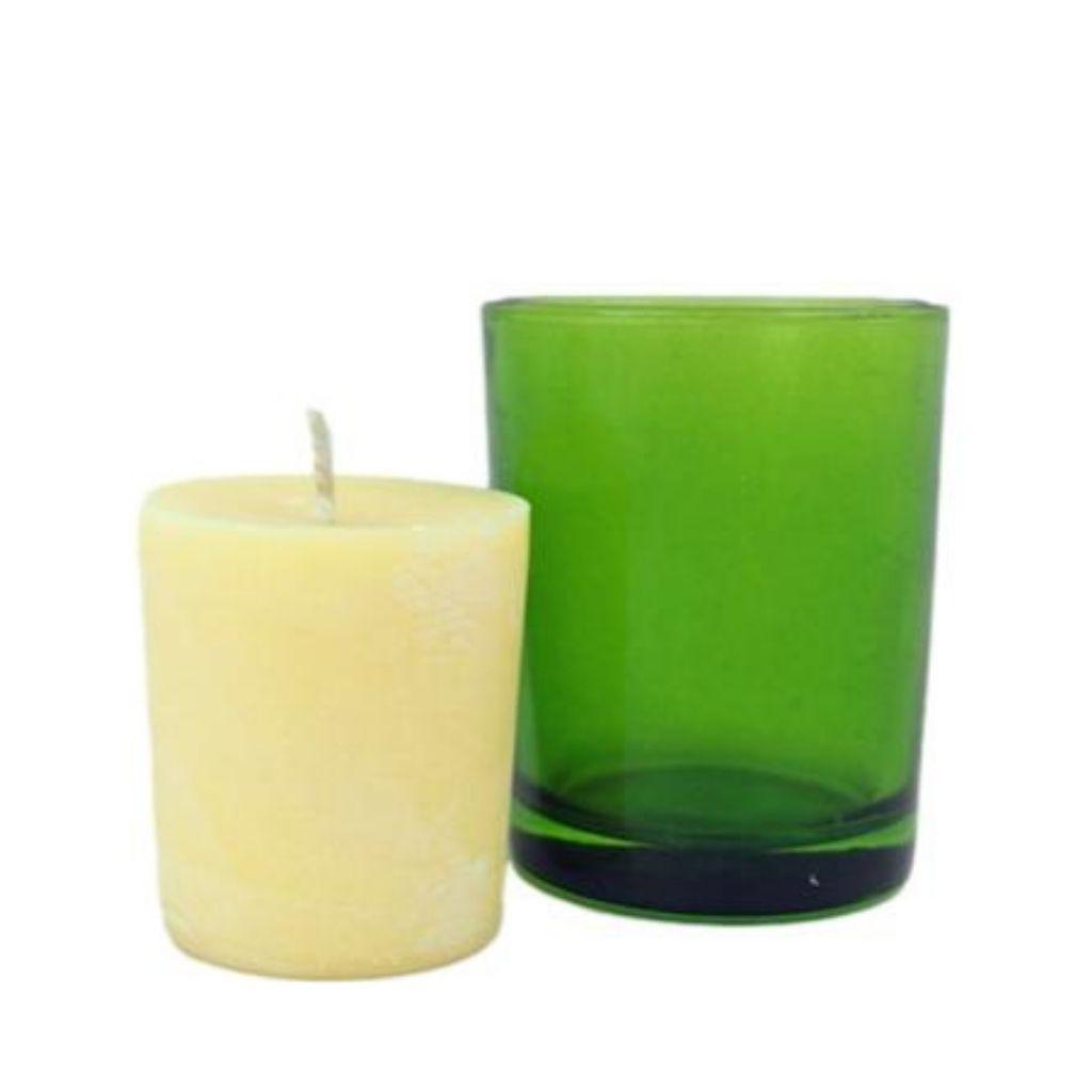 Relaxing votive candle next to green straight walled votive candle holder