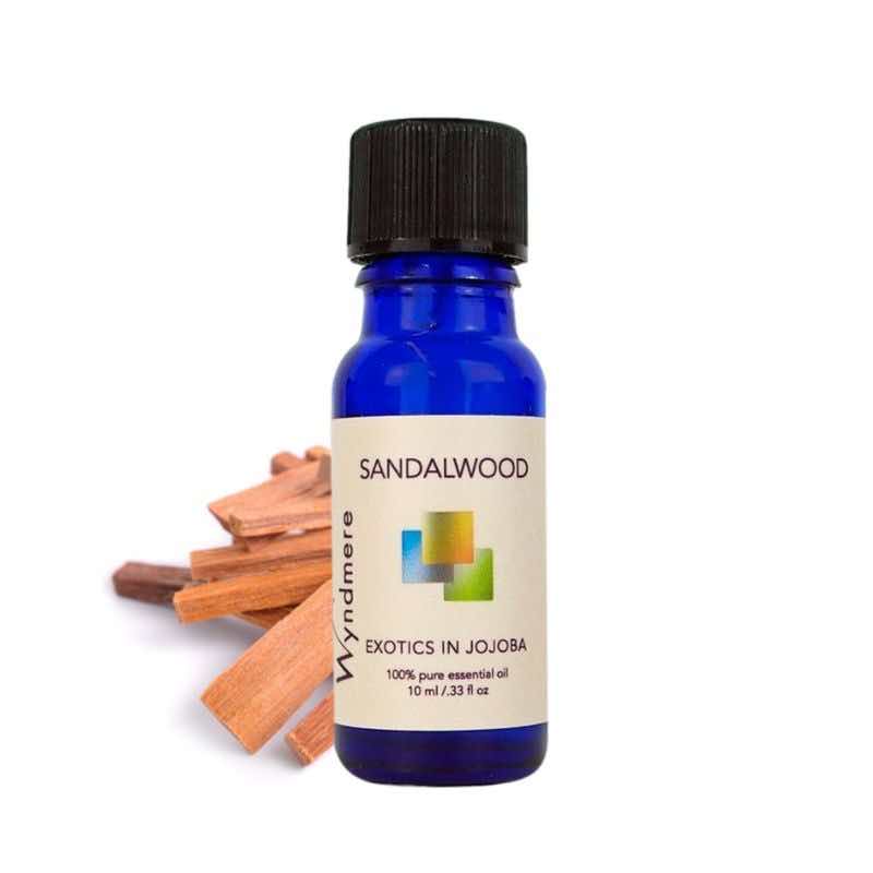 Sandalwood wood chips with a 10ml cobalt blue bottle of Wyndmere Sandalwood Essential Oil diluted in Jojoba