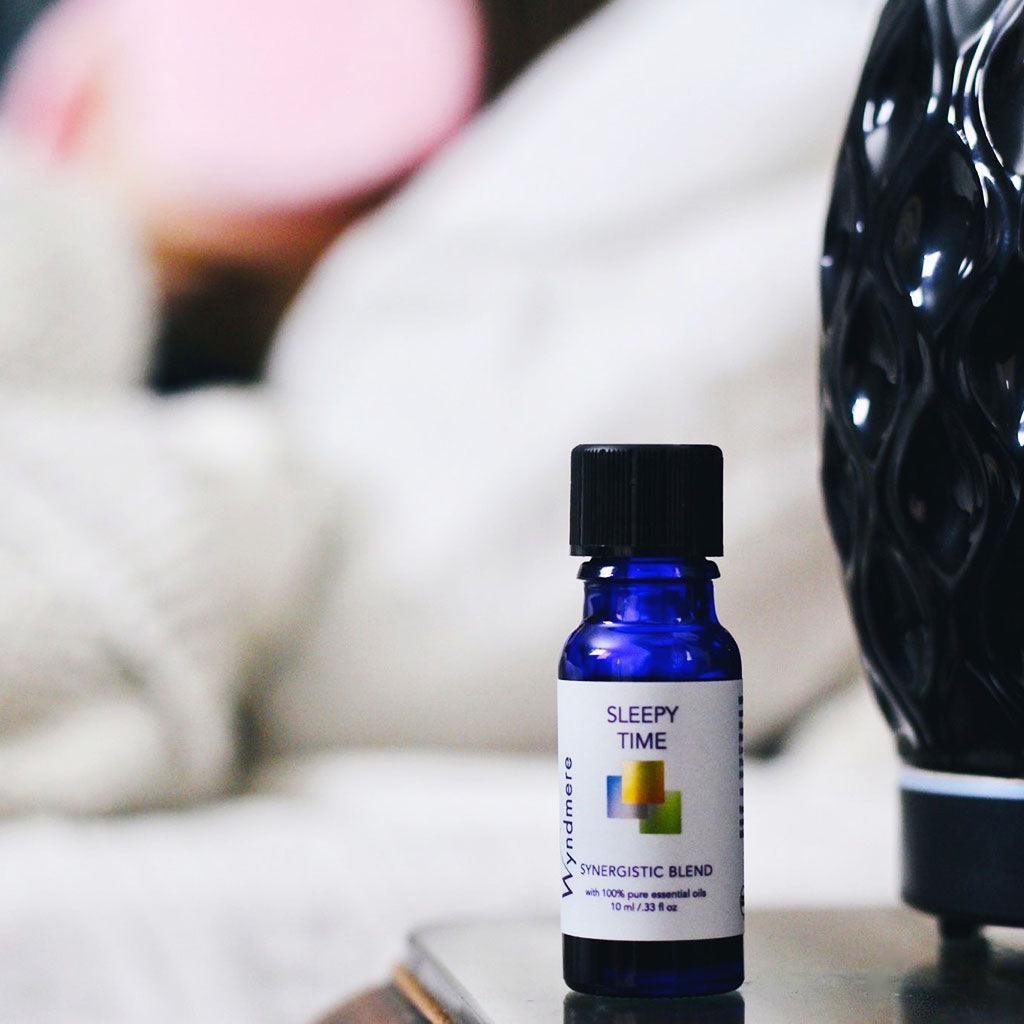 Bottle of Sleepy Time essential oil blend and aroma vase diffuser with sleeping woman in background