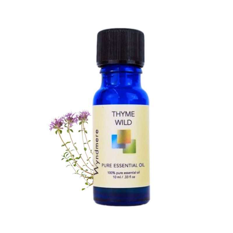 Wild thyme flowers with a 10ml cobalt blue bottle of Wyndmere Thyme Wild Essential Oil