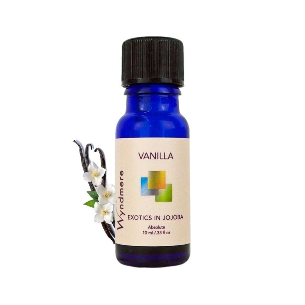 Vanilla pods and flowers with a 10ml cobalt blue bottle of Wyndmere Vanilla Absolute Oil diluted in Jojoba