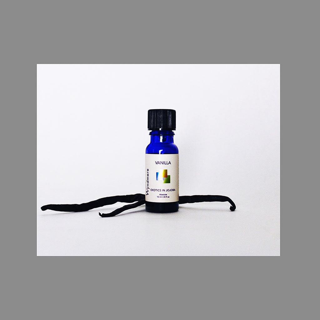 Vanilla pods with a 10ml cobalt blue bottle of Wyndmere Vanilla Absolute Oil diluted in Jojoba