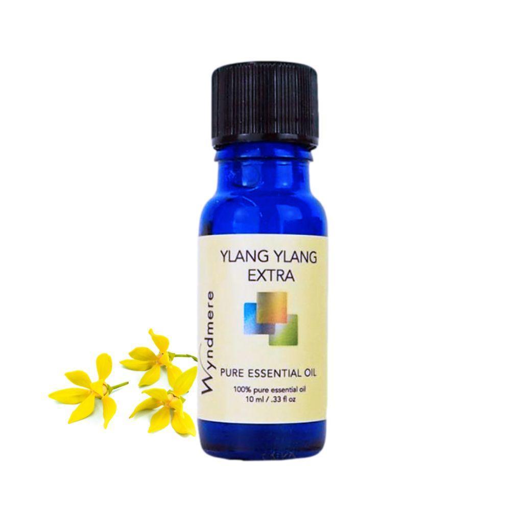 Ylang Ylang flowers with a 10ml cobalt blue bottle of Wyndmere Ylang Ylang Essential Oil